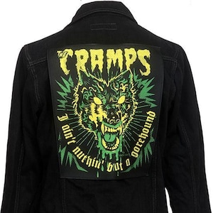 May include: Black denim jacket with a large patch featuring a green and yellow wolf illustration and the text "THE CRAMPS". The patch also includes the phrases "I ain't nuthin' but a gorehound".