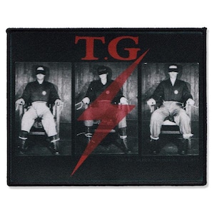 May include: Black patch with a grayscale image of three figures seated in chairs, each wearing a blindfold. A large red lightning bolt graphic is superimposed. The letters "T.G" are in red at the top of the patch.