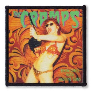 Peut inclure: Un patch noir et blanc avec une image colorée d'une femme en bikini tenant une guitare. Le texte "The Cramps" est en lettres vertes et le texte "Songs the Lord Taught Us" est en lettres blanches. L'arrière-plan est un motif orange et brun tourbillonnant.