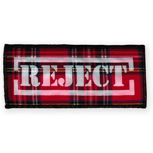 May include: Red and black tartan fabric patch with white stitching and the word "REJECT" printed in white inside a white rectangle.
