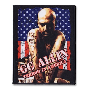 May include: A black and red embroidered patch featuring a portrait of GG Allin, a punk rock musician, in front of an American flag. The text "GG Allin Terror in America" is written in white letters on the patch.