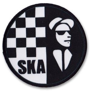 Könnte beinhalten: Schwarzer und weißer runder Patch mit einem karierten Muster auf der linken Seite und einer Silhouette einer Person mit Hut und Sonnenbrille auf der rechten Seite. Das Wort "SKA" ist in Weiß auf der karierten Seite gedruckt.