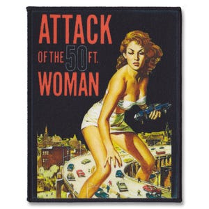 Op de afbeelding: Een zwart en rood geborduurde patch met de tekst "Attack of the 50 ft. Woman" en een vrouw in een witte jurk die op een snelweg staat met auto's die voorbijrijden.
