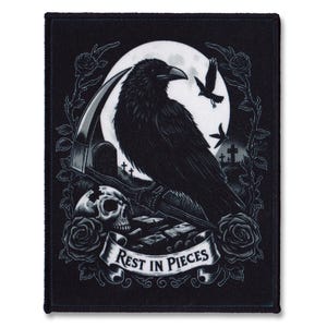 Op de afbeelding: Zwart-witte geborduurde patch met een raaf die op een zeis zit voor een volle maan. De raaf is omringd door rozen en de tekst "Rest in Pieces" staat op een banner onder de raaf.