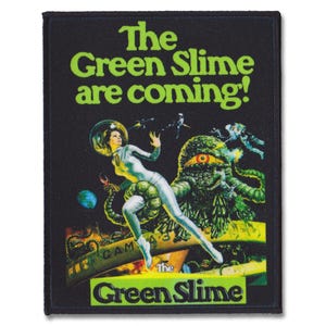 May include: A black and green patch with the text "The Green Slime are coming!" and a graphic of a woman in a space suit riding a green monster with a large eye.