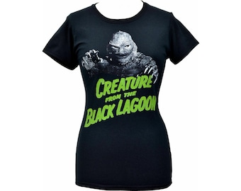 May include: Black t-shirt featuring a graphic of the Creature from the Black Lagoon in grayscale, with the text "CREATURE FROM THE BLACK LAGOON" in green. The shirt has short sleeves and a crew neck.