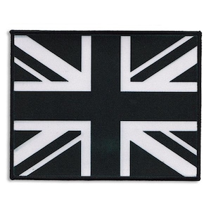 Puede incluir: Un parche rectangular con la Union Jack, la bandera del Reino Unido. El diseño es en blanco y negro, con un borde negro. La cruz y las rayas diagonales de la bandera son claramente visibles.