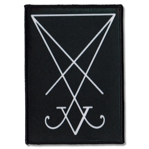 Könnte beinhalten: Schwarzer rechteckiger Aufnäher mit einem weißen, umgekehrten Dreieck, sich kreuzenden Linien und einem V-förmigen Symbol. Der Aufnäher hat einen schwarzen Rand und ist wahrscheinlich ein Emblem oder Symbol.