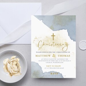 Può includere: Un invito di battesimo in acquerello blu e oro. L'invito presenta una croce e il testo "Battesimo", "Si prega di unirsi a noi per il battesimo di Matthew & Thomas", "Alle cinque in punto di sabato diciotto febbraio nella chiesa di San Michele, Warrington", "Festa successiva al 157 Wellington Road", e "RSVP entro il 14 febbraio al 123".