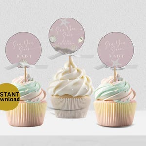 Puede incluir: Tres cupcakes con glaseado pastel y adornos decorativos. Los adornos son redondos con el texto "Sea You Soon BABY" y un gráfico de estrella de mar. Los cupcakes tienen una combinación de colores rosa claro, amarillo y verde. La imagen también incluye un gráfico de "DESCARGA INSTANTÁNEA".