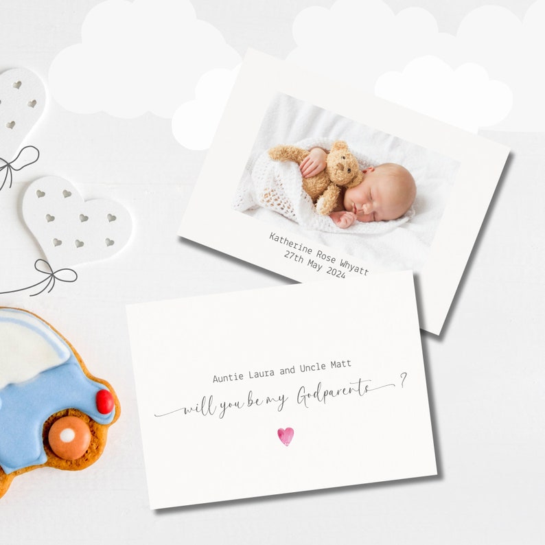 May include: A white card with a photo of a baby sleeping with a teddy bear. The text on the card reads "Katherine Rose Whyatt 27th May 2024" and "Auntie Laura and Uncle Matt will you be my Godparents?"