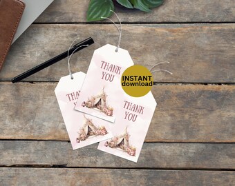 Op de afbeelding: Drie witte cadeaulabels met de tekst "THANK YOU" in een donkerroze lettertype. Elk label heeft een aquarel illustratie van een tipi met bloemaccenten. Een zwarte pen en een bruin leren notitieboek zijn ook zichtbaar.