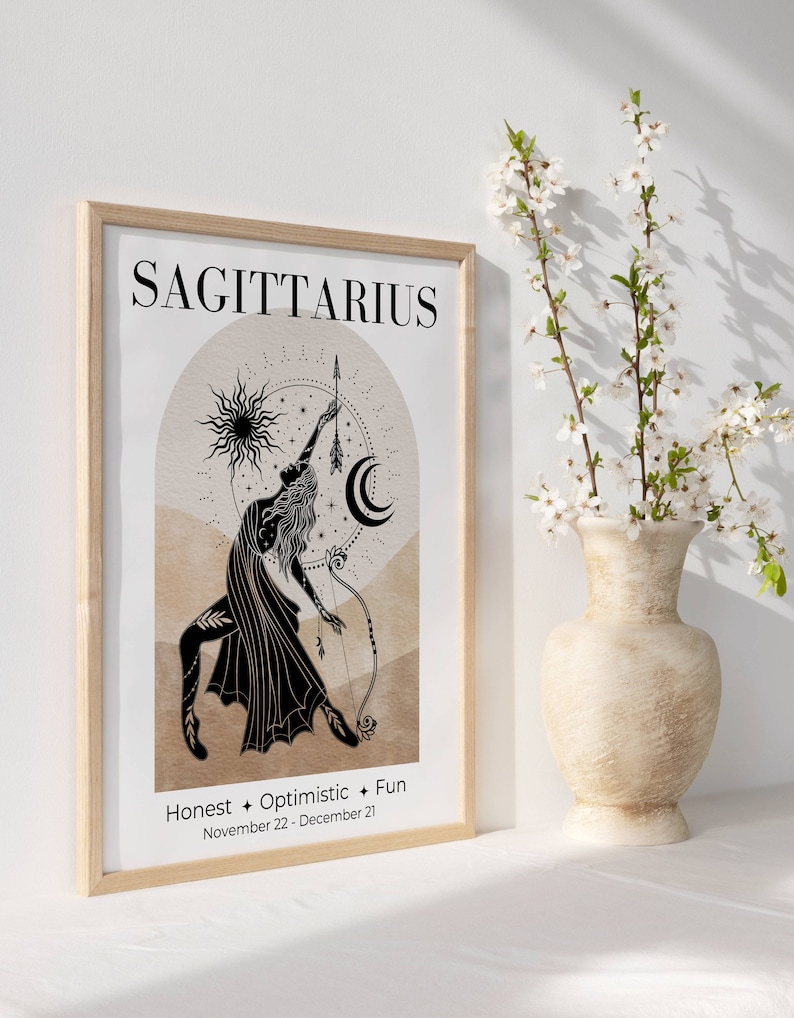 May include: A framed Sagittarius zodiac art print. The print features a black illustration of a figure with a bow and arrow, set against a beige and brown background. The word "SAGITTARIUS" is at the top, with "Honest + Optimistic + Fun" and the dates November 22 - December 21 below.