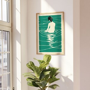 May include: A framed illustration of a woman sitting in a pool of water. The woman is facing away from the viewer and has dark hair. The water is a vibrant teal color and the background is a light cream color.