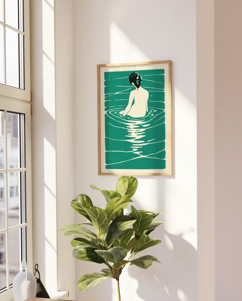 May include: A framed illustration of a woman sitting in a pool of water. The woman is facing away from the viewer and has dark hair. The water is a vibrant teal color and the background is a light cream color.