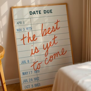 May include: A framed print with a white background and horizontal blue lines, resembling a library card. The print features the words "DATE DUE" at the top and the phrase "the best is yet to come" in red cursive. Dates are listed below.