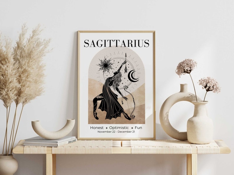 May include: A framed Sagittarius zodiac art print. The artwork features a black illustration of a figure with a bow and arrow, set against a beige and tan background. Text includes "Sagittarius", "Honest + Optimistic + Fun", and the dates November 22 - December 21.