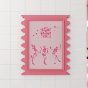 Puede incluir: Una impresi&oacute;n enmarcada en rosa con un fondo rosa que presenta tres esqueletos bailando bajo una bola de discoteca. El marco tiene un borde festoneado.