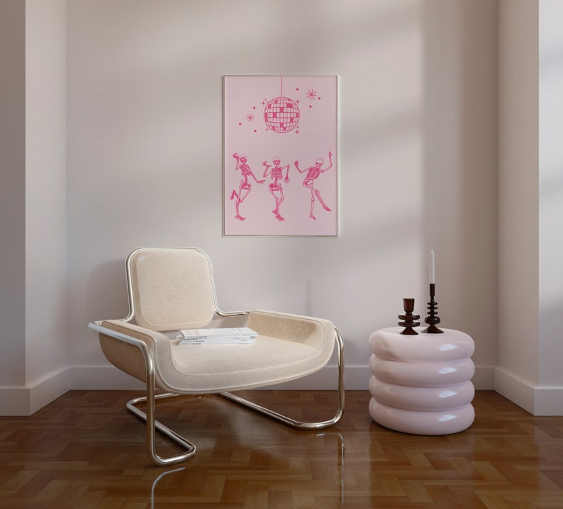 Puede incluir: Un sill&oacute;n blanco con marco cromado se encuentra en una habitaci&oacute;n con suelo de madera clara. Una mesa auxiliar rosa de tres niveles se encuentra junto al sill&oacute;n. Una impresi&oacute;n enmarcada con fondo rosa y una bola de discoteca colgando del techo con tres esqueletos bailando debajo est&aacute; colgada en la pared.