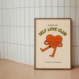 May include: A framed print with a cartoon heart hugging itself. The text reads "Membership Pass Self Love Club" and "I am worthy of all things good".