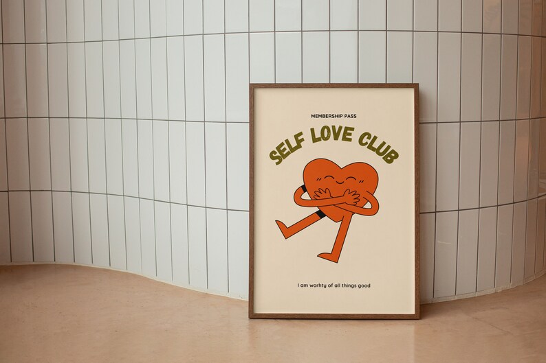 May include: A framed print with a cartoon heart hugging itself. The text reads "Membership Pass Self Love Club" and "I am worthy of all things good".