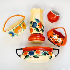 May include: A set of five vintage ceramic pieces with hand-painted floral designs in shades of orange, blue, green, and white. The pieces include a vase, a bowl, a creamer, and two small baskets.