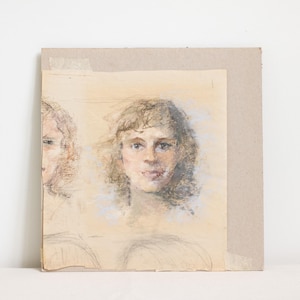 May include: A pastel drawing of two faces on a beige background. The drawing is framed with a brown cardboard mat.