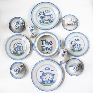 May include: A set of three ceramic mugs with a speckled, matte finish. The mugs are in shades of cream, light gray, and dark gray. Each mug has a simple, minimalist design and a rounded handle.