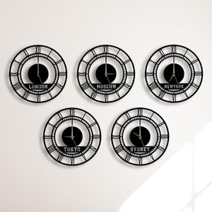 May include: Five black metal wall clocks with Roman numeral markings and gold accents. Each clock features a different city name: London, Moscow, New York, Tokyo, and Sydney.