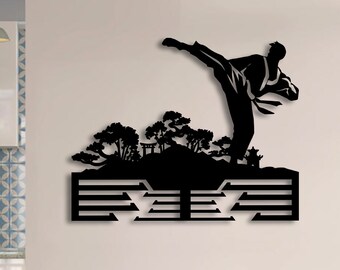 May include: Black metal wall art featuring a silhouette of a martial artist kicking in mid-air, with a stylized mountain and trees behind them. The art piece has a geometric design with multiple horizontal lines.
