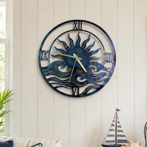 May include: A circular metal wall clock featuring a blue and bronze sun and ocean wave design. The clock face displays Roman numerals at the twelve, three, six, and nine o'clock positions, with thin gold-colored hour and minute hands centered.