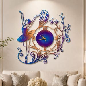 May include: A wall clock featuring a ballerina design. The clock has a gradient of blue, purple, and copper colors. The ballerina is in a graceful pose, with arms raised. The clock face is circular, with numbers and hands. The clock is surrounded by decorative floral elements.