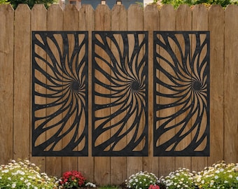 May include: Three black metal decorative panels with a swirling, abstract design are mounted on a wooden fence. The panels are rectangular and feature a repeating pattern of curved lines radiating from a central point. The fence is made of vertical wooden planks.