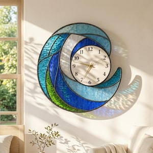May include: A decorative wall clock in the shape of a wave, featuring a cream-colored clock face with black numerals and gold hands. The wave design incorporates shades of blue, green, and white, with a black border. The clock is mounted on a cream-colored wall.