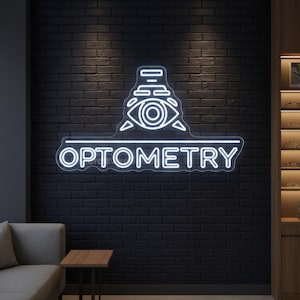May include: A white neon sign with the word OPTOMETRY below an eye-shaped graphic. The sign is mounted on a black brick wall. The room also features a gray sofa, a small wooden table, and a display case with eyeglasses.