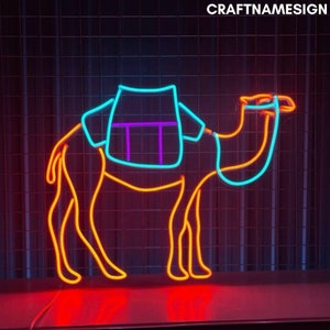 May include: A neon sign shaped like a camel with a turquoise saddle and purple straps. The camel is outlined in orange neon.
