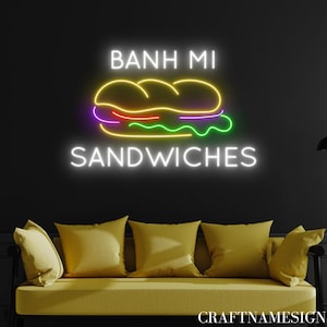 May include: Neon sign with the text "Banh Mi Sandwiches" in white with a yellow neon outline. The sign also features a yellow neon outline of a sandwich with purple, red, and green neon fillings.