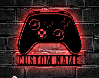 May include: A black and red custom gamer controller night light with a remote control. The light features a custom name, "CUSTOM NAME", below the controller.