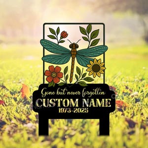 May include: A black metal garden sign featuring a dragonfly, flowers, and the inscription "Gone but never forgotten". It has space for a custom name and dates.