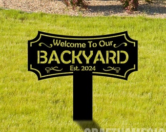 Puede incluir: Señal de jardín de metal negro con texto dorado que dice "Bienvenido a nuestro patio trasero Est. 2024".