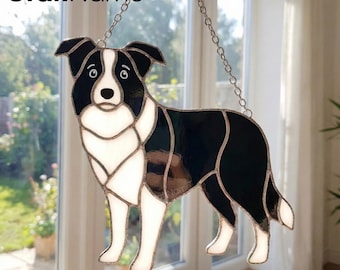 May include: A stained glass suncatcher shaped like a Border Collie dog with black and white glass segments joined by metal solder lines. The piece features a silver-colored metal chain for hanging and includes the text CraftName sign at the top.