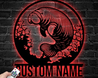 May include: A circular black metal wall sign featuring a cutout silhouette of a manatee surrounded by coral, illuminated by a red LED light ring. Below the circular frame, the text CUSTOM NAME is displayed in bold, black, capital letters.