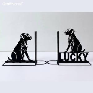 以下が含まれることがあります： 黒い金属製のブックエンドで、座っているラブラドールレトリバーのシルエットと、ベースに「LUCKY」という文字が書かれています。
