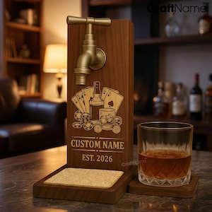 May include: A wooden whiskey dispenser featuring a brass-colored tap, a laser-engraved design of playing cards, a bottle, and dice, with the text CUSTOM NAME and EST. 2026. Includes a square cork coaster base and a glass of amber liquid.