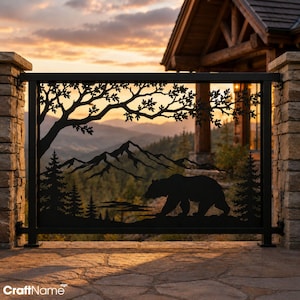May include: A rectangular black metal railing panel featuring a laser-cut silhouette design of a walking bear, pine trees, and mountain peaks beneath the branches of an oak tree. The metal panel is framed by a sturdy black metal border.