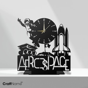 Op de afbeelding: Zwarte metalen klok met een astronaut, een raket en een rover. De wijzerplaat van de klok heeft gouden wijzers en de woorden "ARCSPACE" staan onder de wijzerplaat.