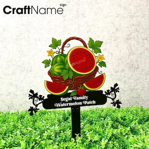 Op de afbeelding: Zwart metalen tuinbord met een watermeloen thema. Het bord toont een mand met watermeloenen, watermeloen schijfjes en de tekst "Segal Family Watermelon Patch."