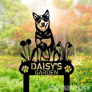 Puede incluir: Señal de jardín de metal negro con una silueta de un perro sentado en la hierba con flores. El letrero dice "Daisy's Garden" con huellas de patas a cada lado.