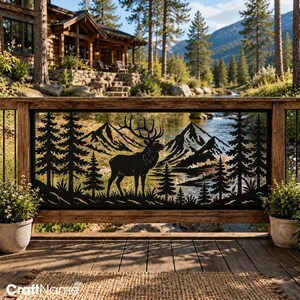May include: A black metal decorative panel featuring a laser-cut silhouette of an elk standing in a forest with pine trees and mountains in the background. The rectangular panel is mounted within a wooden railing frame on a deck.