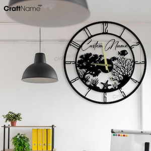 Puede incluir: Reloj de pared de metal negro con un nombre personalizado y una silueta de un arrecife de coral con peces. El reloj tiene marcadores de hora en números romanos y un fondo negro.